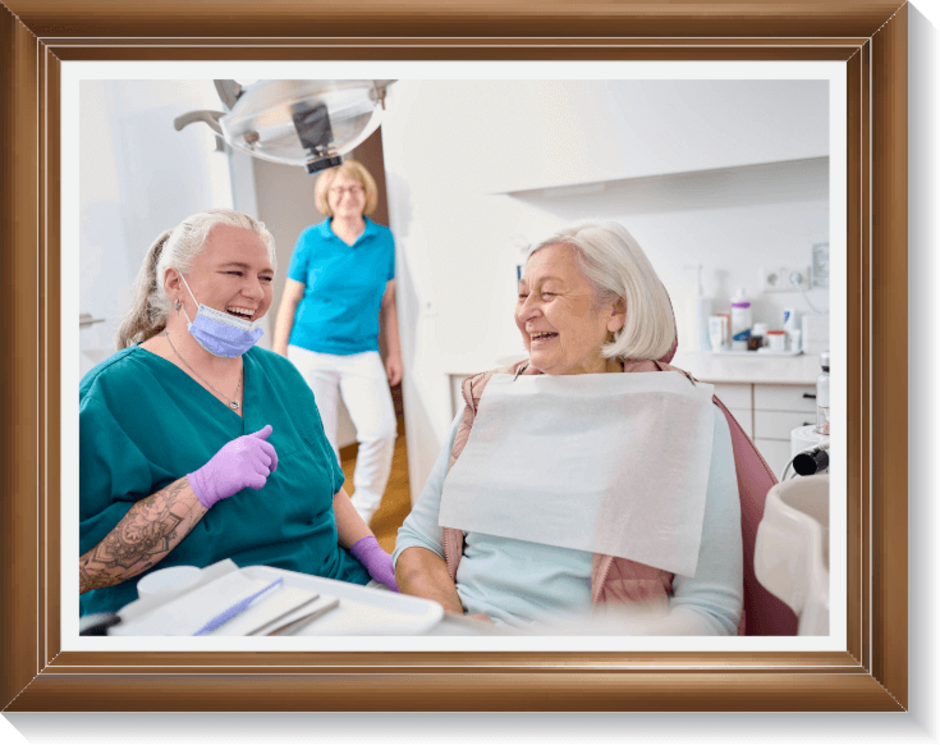 Zahnärztin Dr. Ringler und ihre Mitarbeiterin Frau Becker lachen gemeinsam mit einer Patientin, die in der Zahnarztpraxis Zahnstube in Erlangen in Behandlung ist.