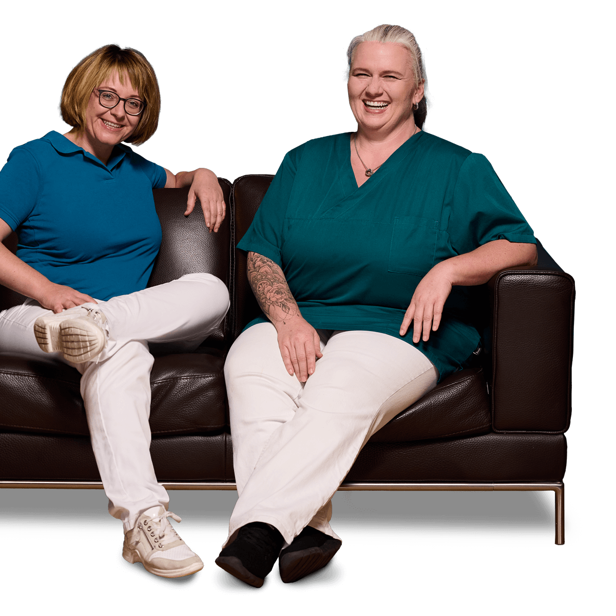 Zahnärztin Dr. Manuela Ringler und ihre Mitarbeiterin Frau Becker sitzen nebeneinander auf einer braunen Ledercouch